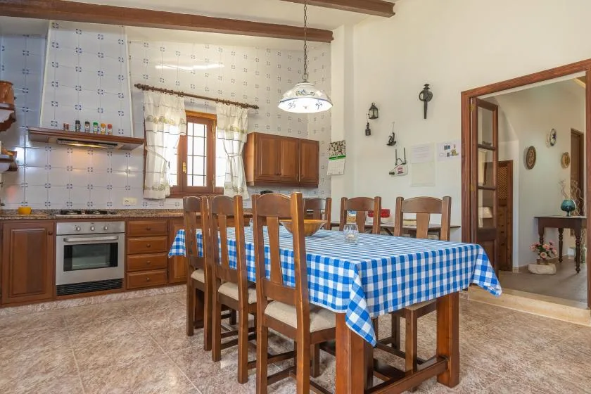 Un comedor con un mantel a cuadros junto a una cocina.