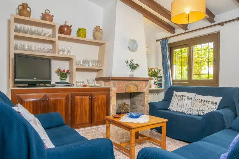 Una sala de estar con asientos azules, una mesa de centro de madera y una chimenea.