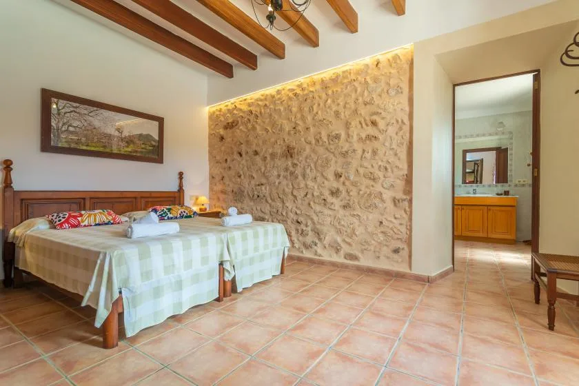 Un dormitorio con una cama junto a una pared de piedra texturizada y una puerta abierta.