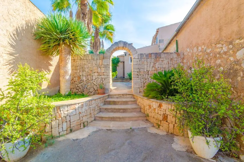 Entrada de patio de piedra con escalones que conducen a un arco.