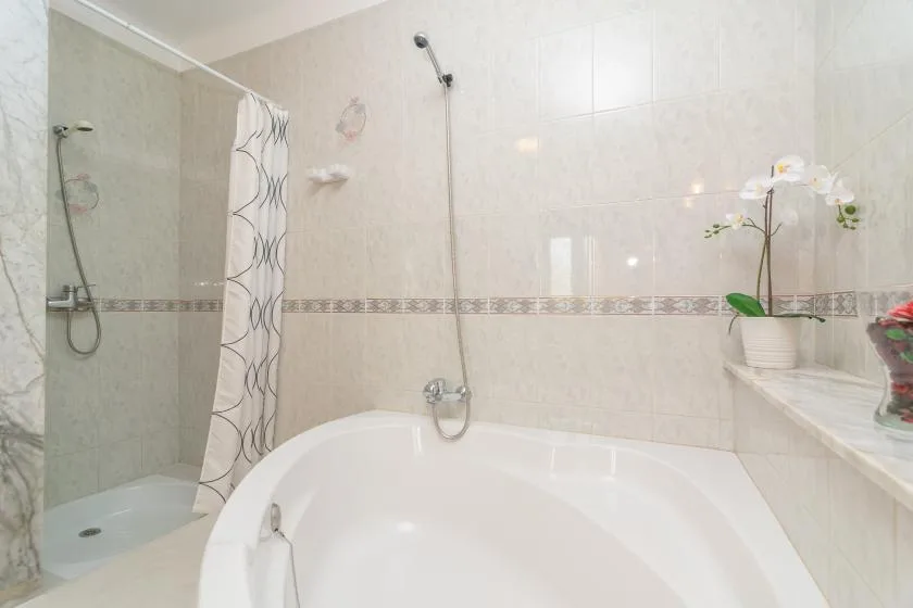 Un baño alicatado con bañera, ducha y cortina estampada.