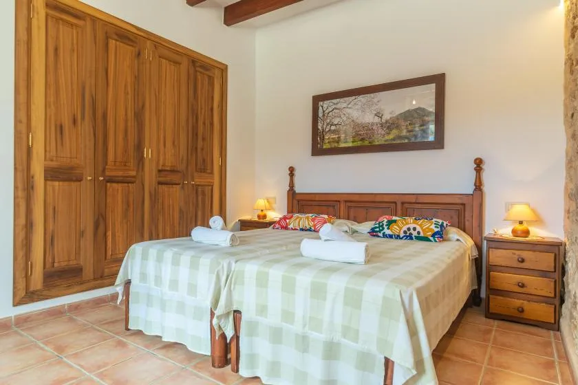 Un dormitorio con una cama de madera, mesitas de noche y un amplio armario empotrado.