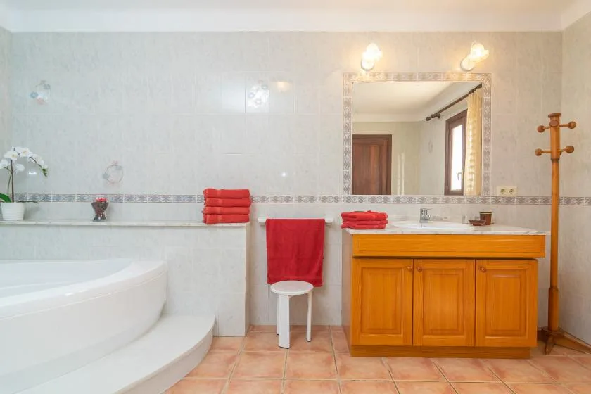 Un baño alicatado con un amplio mueble de madera y una bañera curva.