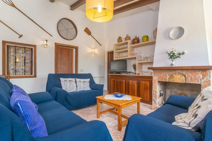 Una sala de estar con asientos azules, una mesa de centro de madera y una chimenea.