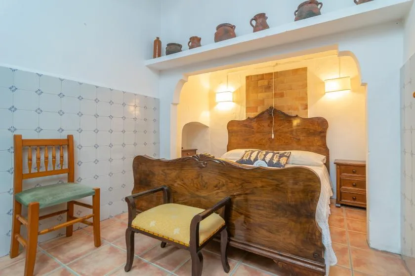 Un dormitorio con una cama de madera y una silla en primer plano.