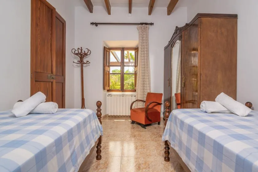 Un dormitorio con dos camas, una ventana y un armario de madera.