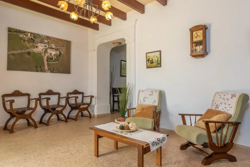 Una sala de estar con asientos de madera, una mesa de centro y cuadros en la pared.