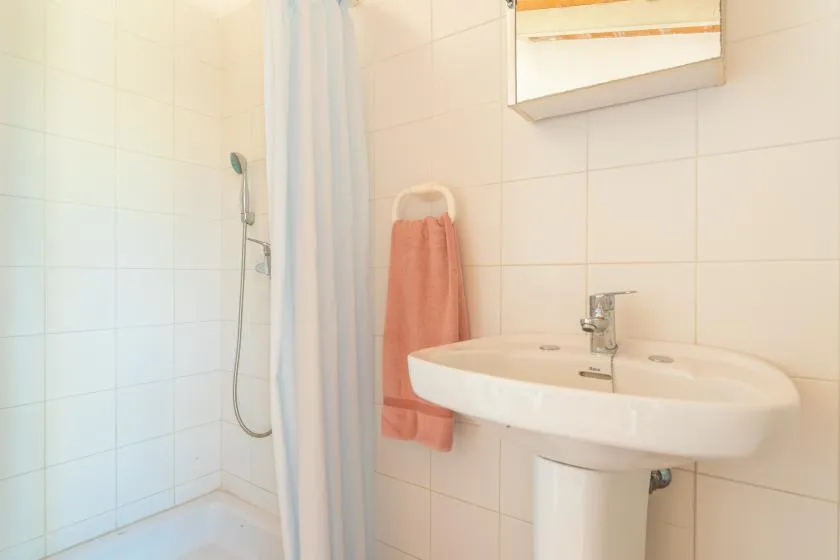 Un baño alicatado con lavabo, cortina de ducha y una toalla colgada.