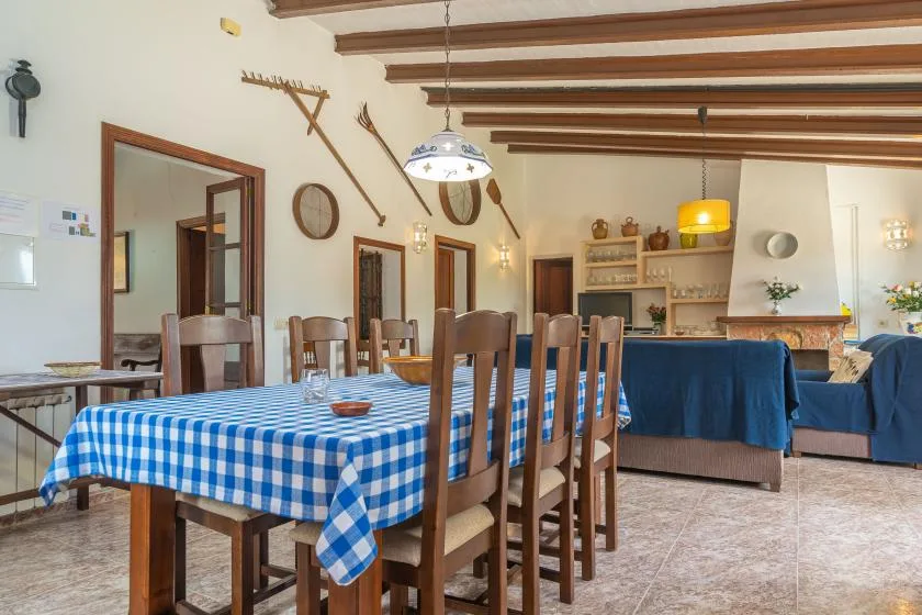 Un comedor con una mesa larga y un mantel de cuadros azules y blancos.