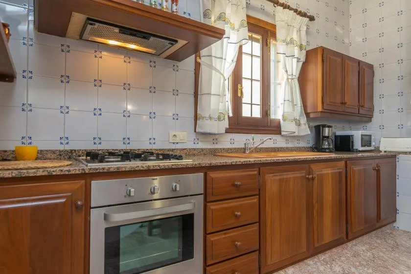 Una cocina con azulejos, armarios de madera, una encimera y una ventana.