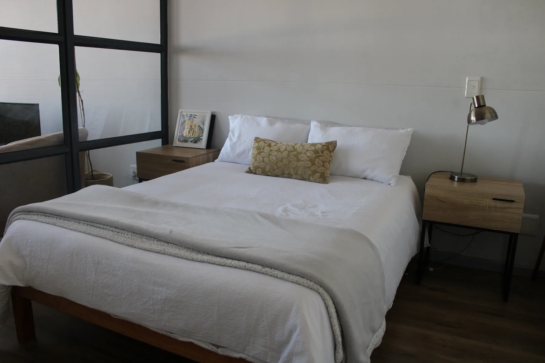 A bedroom with a neatly made bed and bedside tables.