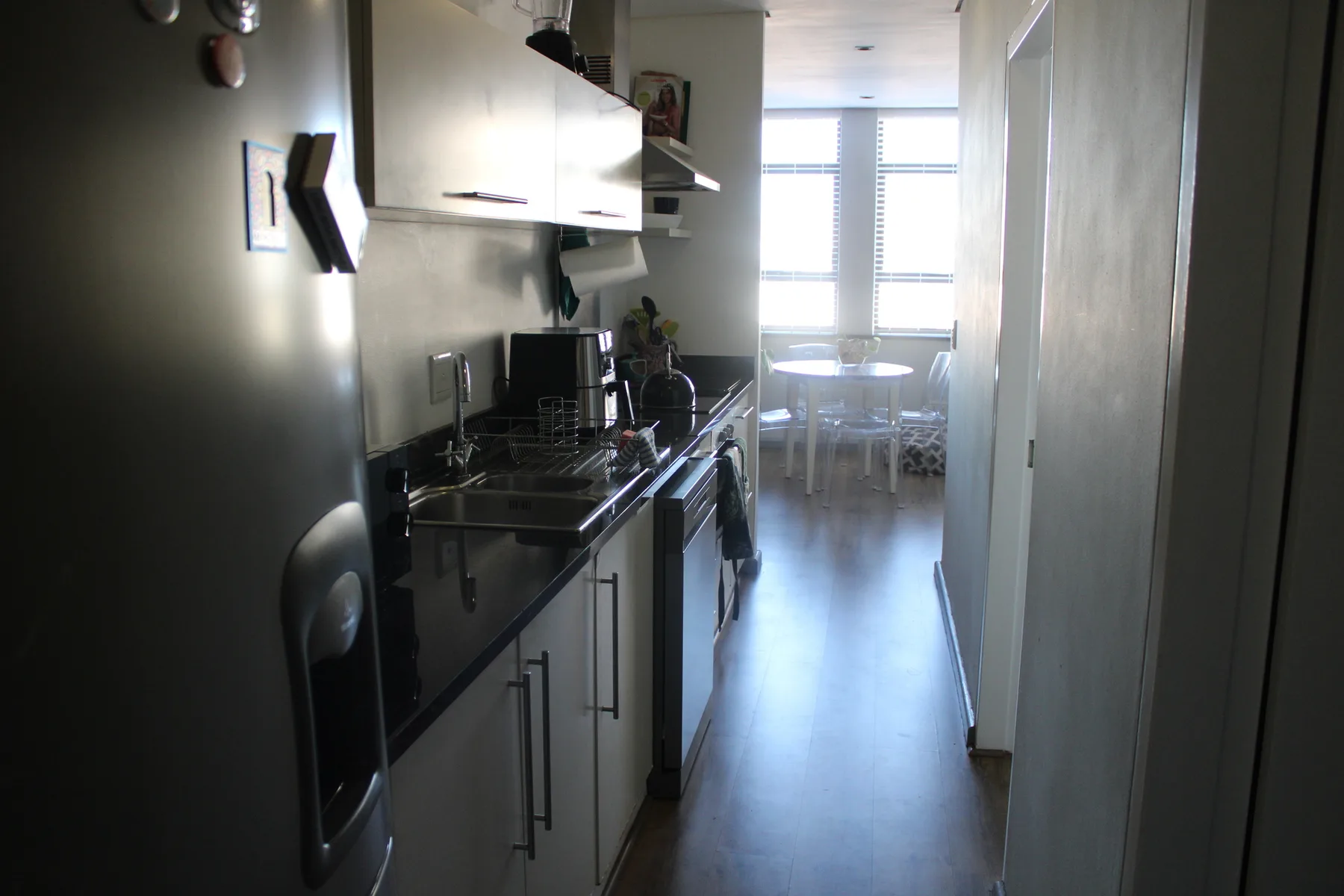 Una cocina estrecha con una mesa de comedor junto a las ventanas.