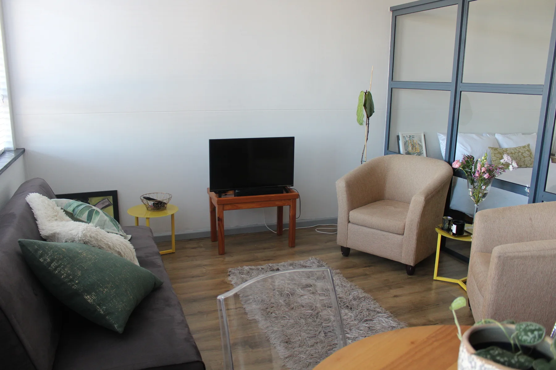 Una sala luminosa con asientos, un televisor y una alfombra pequeña.