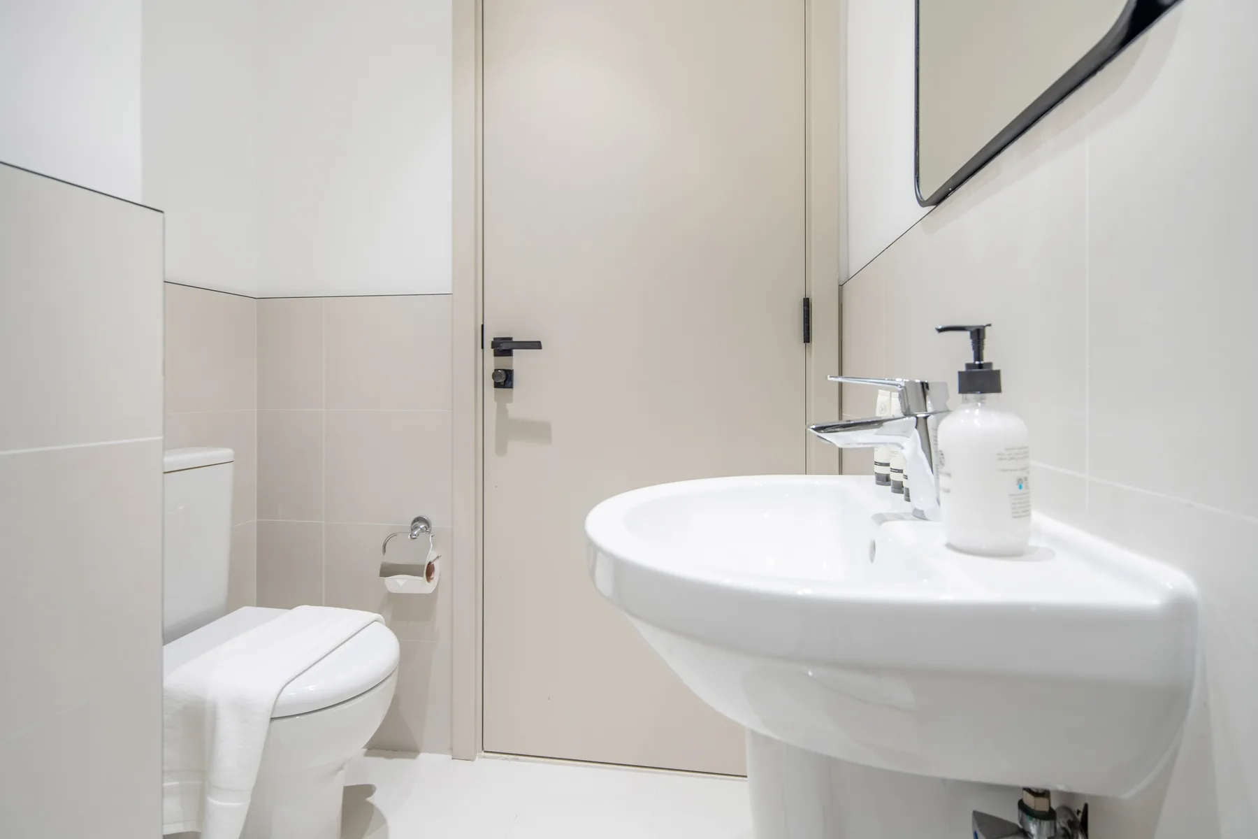 Un baño luminoso con lavabo, inodoro y una puerta cerrada.