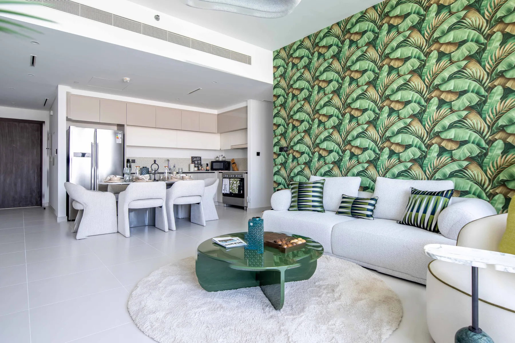 Una sala luminosa con asientos blancos y una pared con estampado de hojas tropicales.