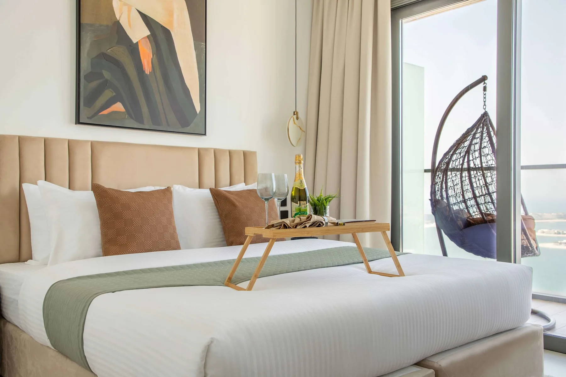 Un dormitorio con una cama bien tendida y una silla colgante junto a la ventana.