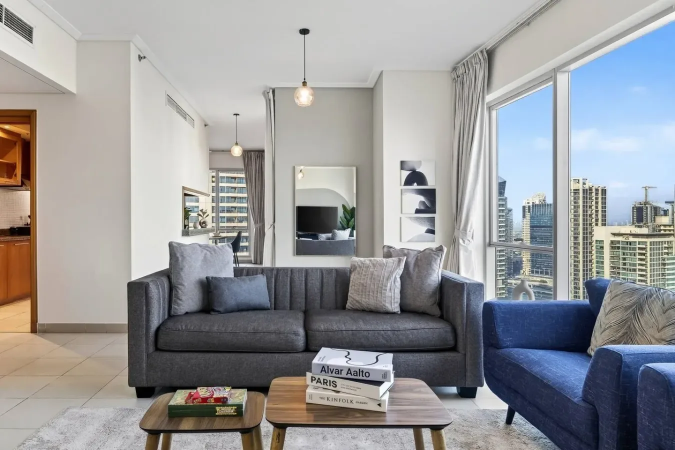 Una sala luminosa con asientos grises y grandes ventanas con vistas a edificios de la ciudad.