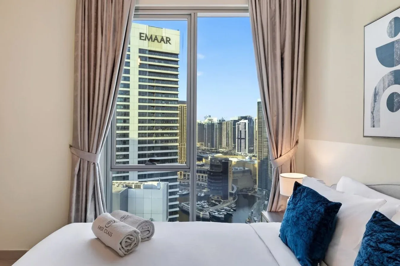 Un dormitorio con una cama bien tendida y vistas de la ciudad por la ventana.