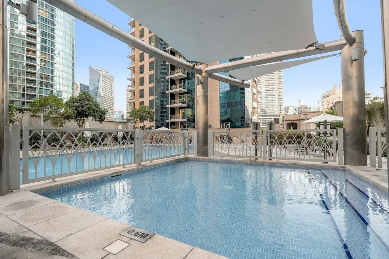 Una piscina en la azotea está bajo un toldo y rodeada de edificios urbanos.
