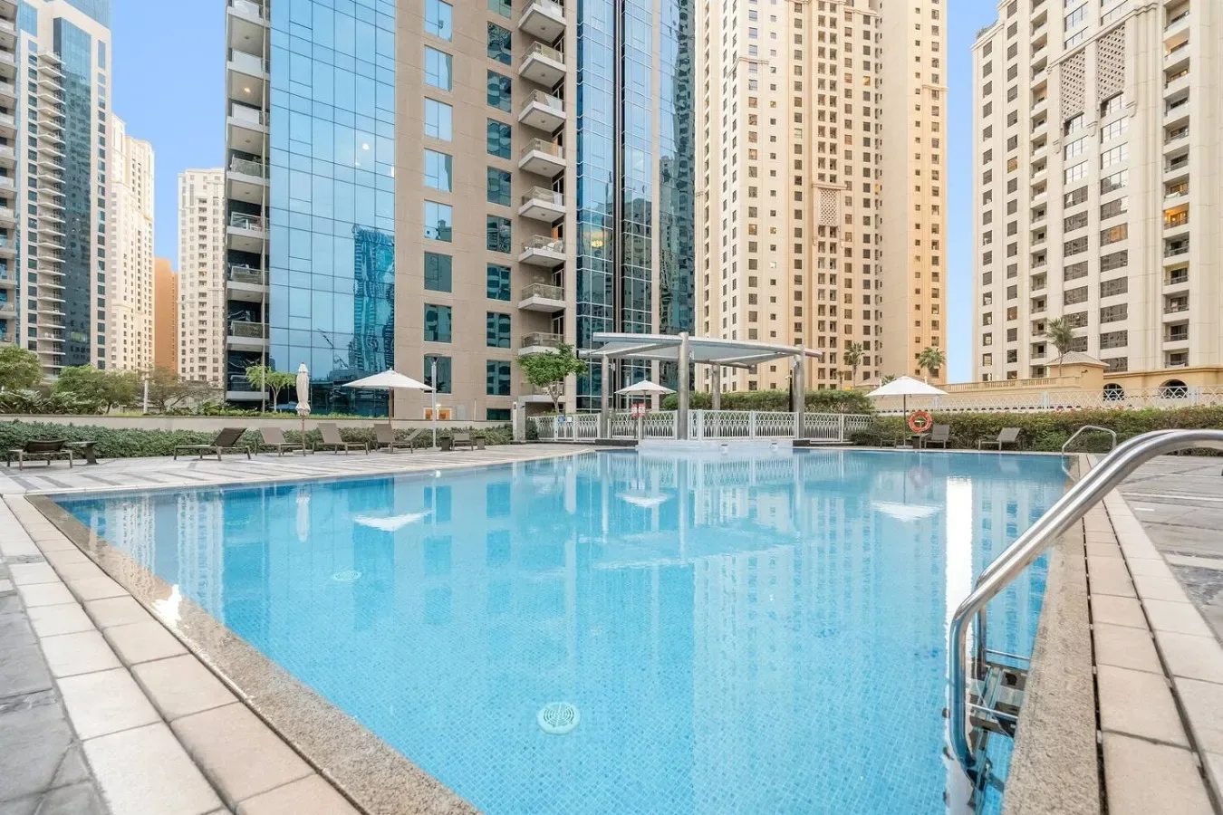 Una piscina al aire libre está rodeada de edificios de apartamentos altos.