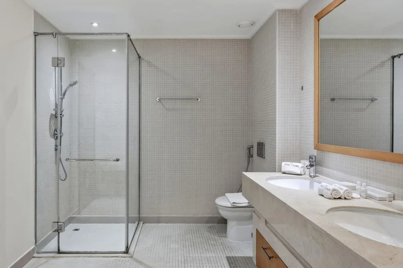 Un baño con azulejos, ducha de vidrio y un lavabo amplio.