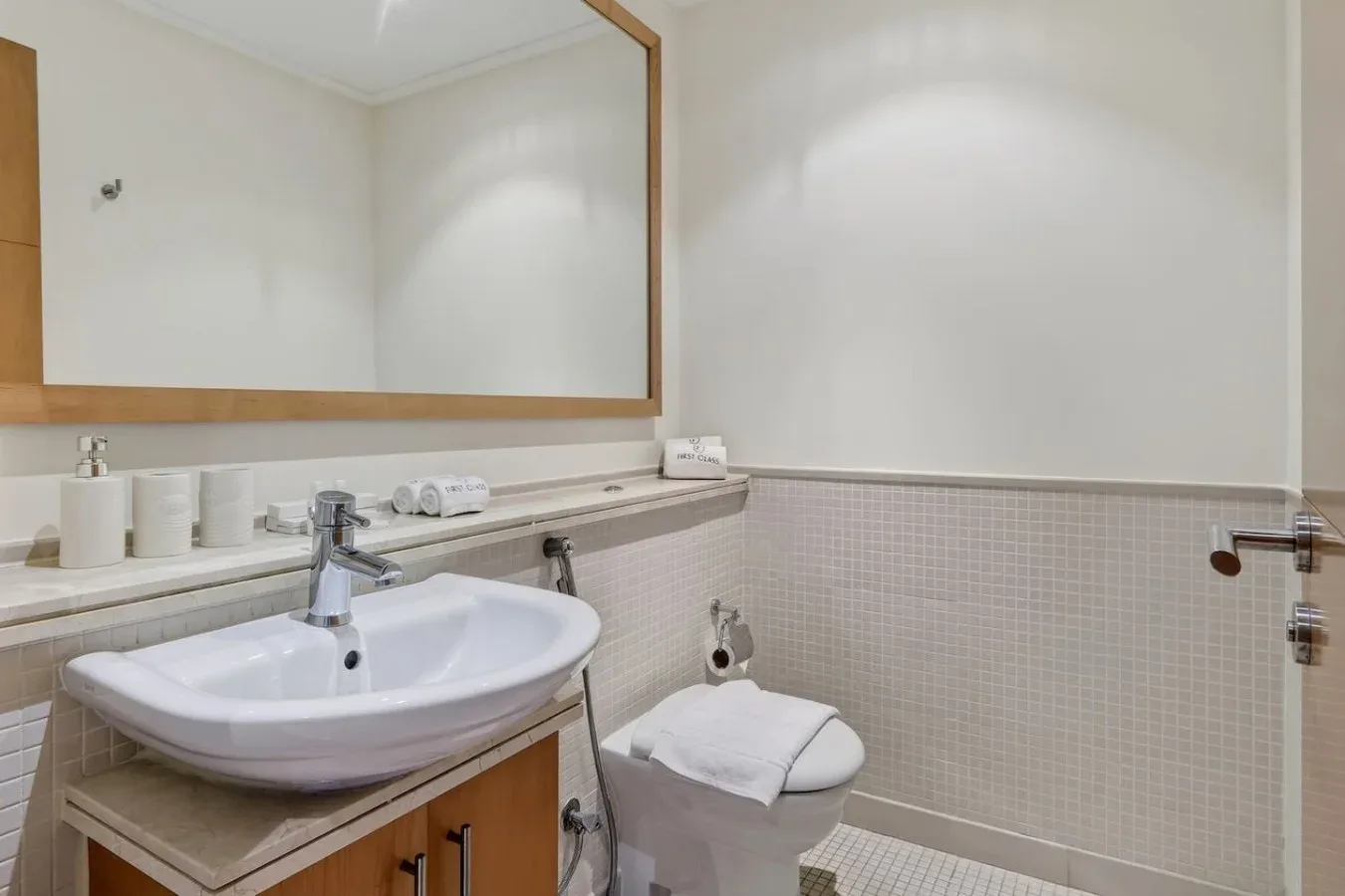 Un baño con lavabo, inodoro y un espejo grande en la pared.