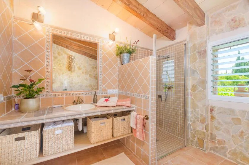 A tiled bathroom with a vanity, mirror, and glass shower.