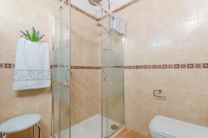 A tiled bathroom with a glass shower and a toilet.