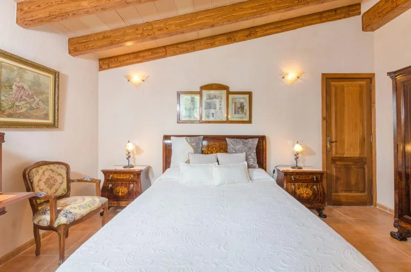 A bedroom with a large bed, bedside tables, and exposed wooden ceiling beams.
