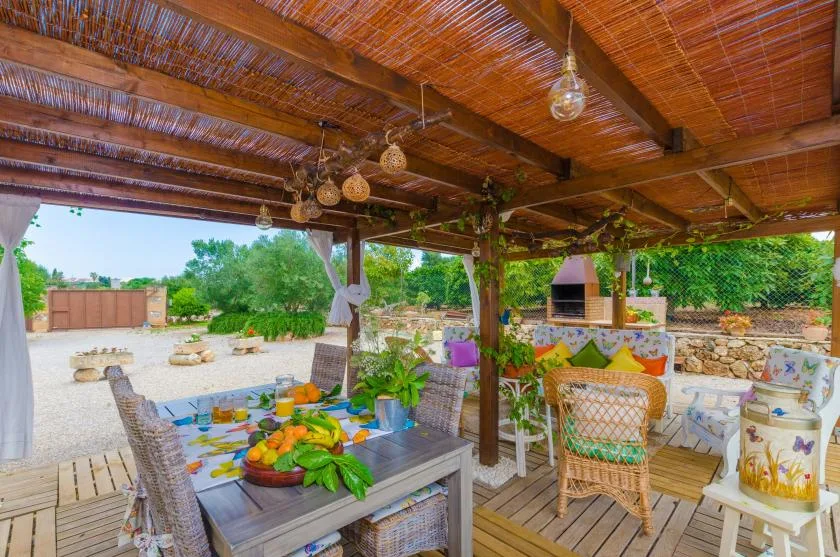 A covered outdoor dining area with a wooden table and garden views.