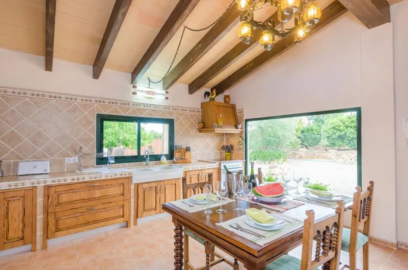 A dining area with a wooden table beside a large window overlooking greenery.