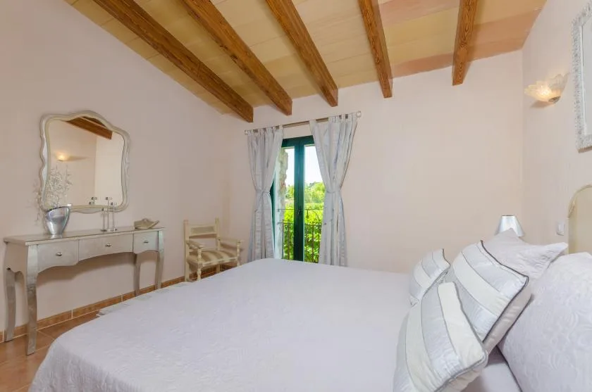 A bedroom with a large bed and a window opening onto greenery.