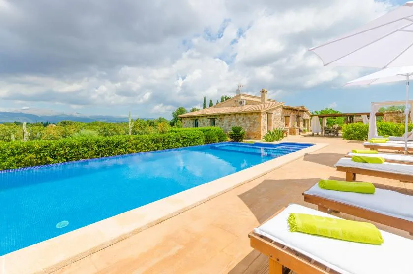 A swimming pool beside a stone building, with loungers along the deck.