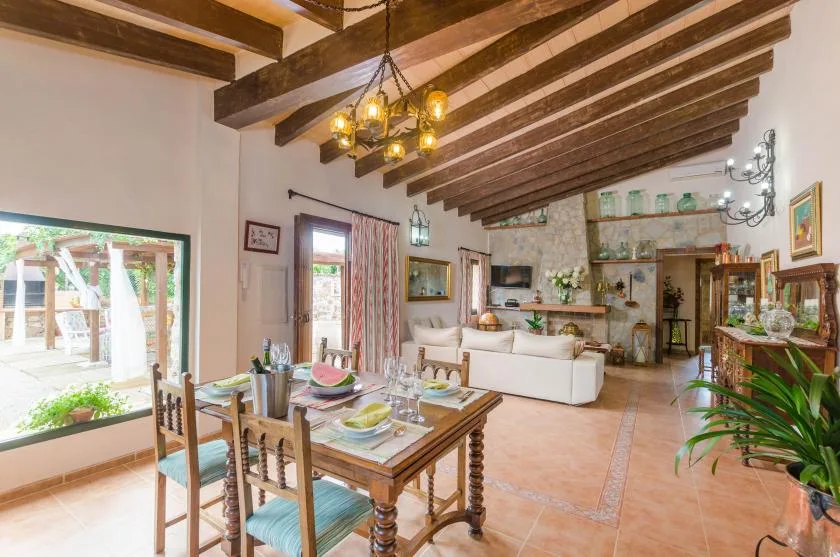 A dining and living room with exposed ceiling beams and a wooden dining table.