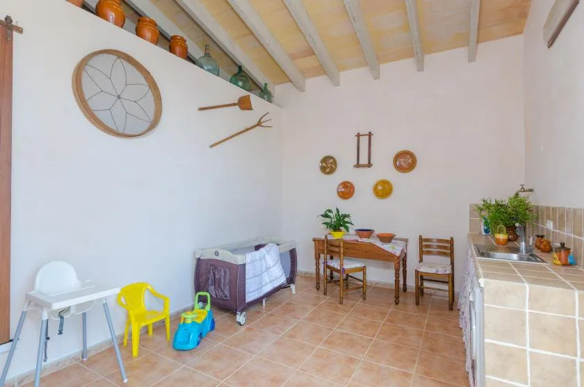 A bright room with a small table and chairs, a playpen, and children’s toys.