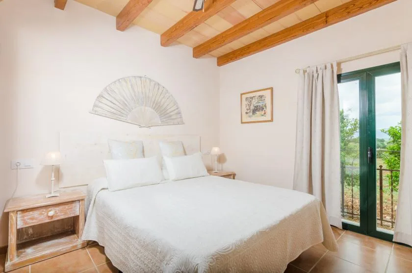 A bedroom with a large bed, bedside tables, and exposed wooden ceiling beams.