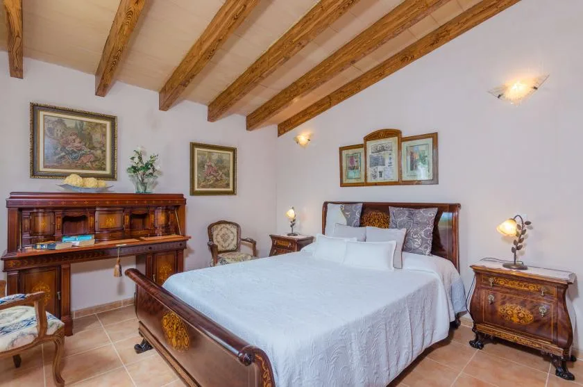 A bedroom with a large bed, wooden furnishings, and exposed ceiling beams.