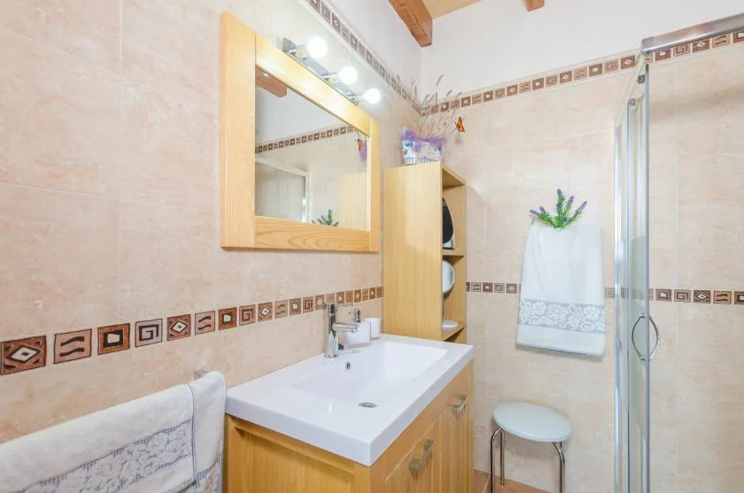 A bathroom with a sink, mirror, and glass shower enclosure.