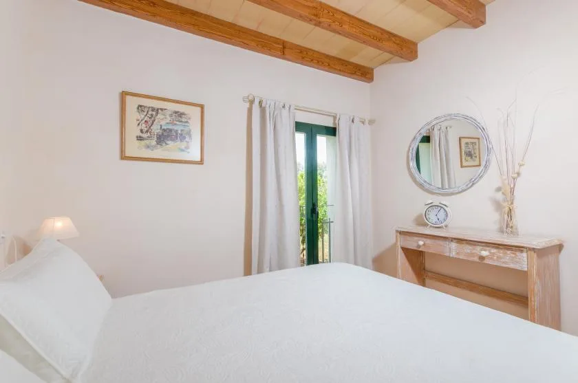 A bedroom with a neatly made bed, framed artwork, and a wooden dresser.