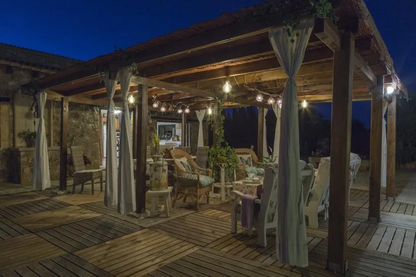 A covered outdoor seating area is lit by hanging lights at dusk.