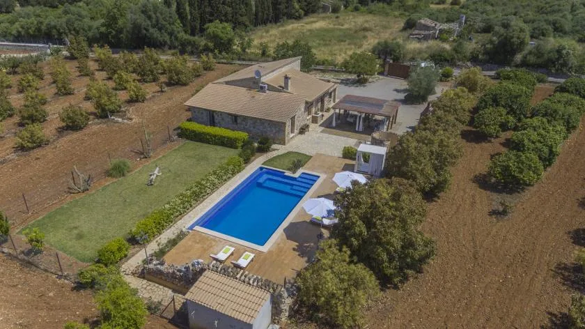 An aerial view of a house and swimming pool surrounded by landscaped grounds.