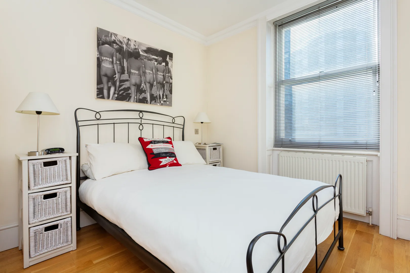 A bedroom with a neatly made bed beneath a large window.