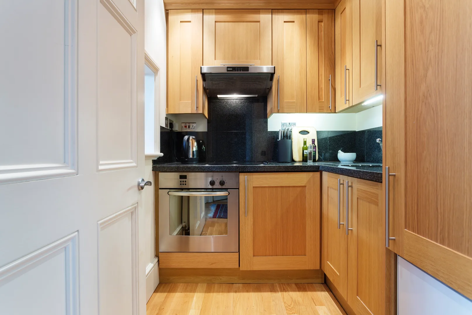 A compact kitchen with wooden cabinets, a stove, and countertop appliances.