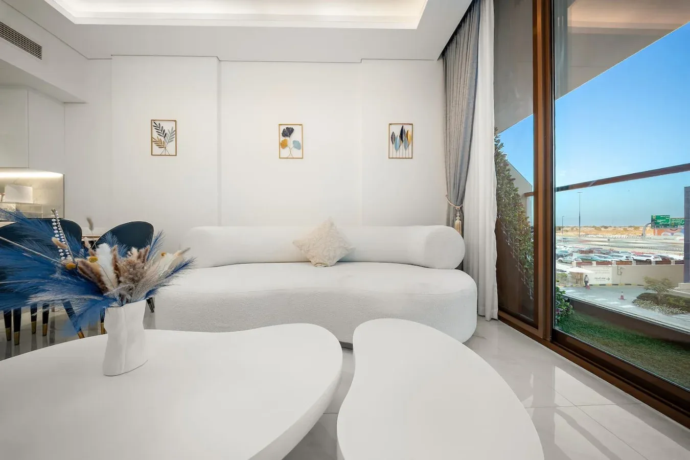 A bright living room with white seating beside a large window overlooking the waterfront.