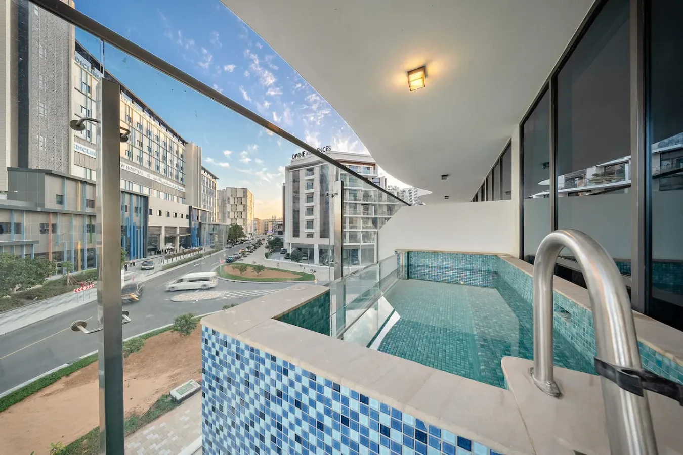 A small tiled pool sits beside glass railings overlooking nearby buildings.