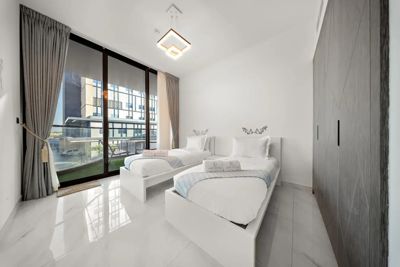 A bright bedroom with two beds beside a large window.