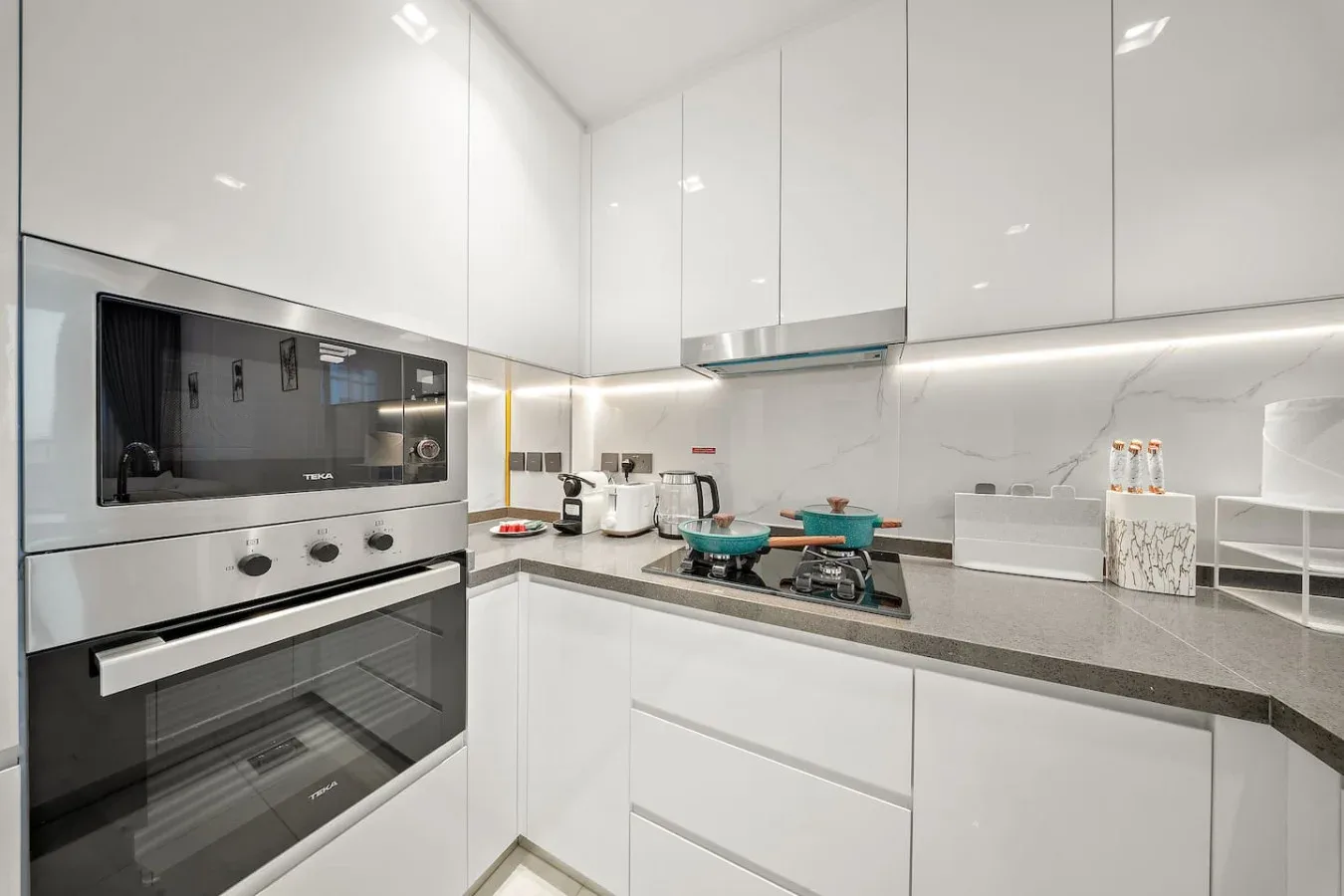 A modern kitchen with built-in appliances, white cabinetry, and a gas cooktop.