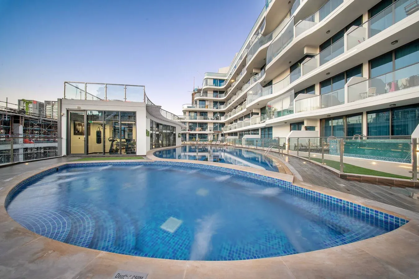 An outdoor swimming pool sits beside a modern multi-story building.