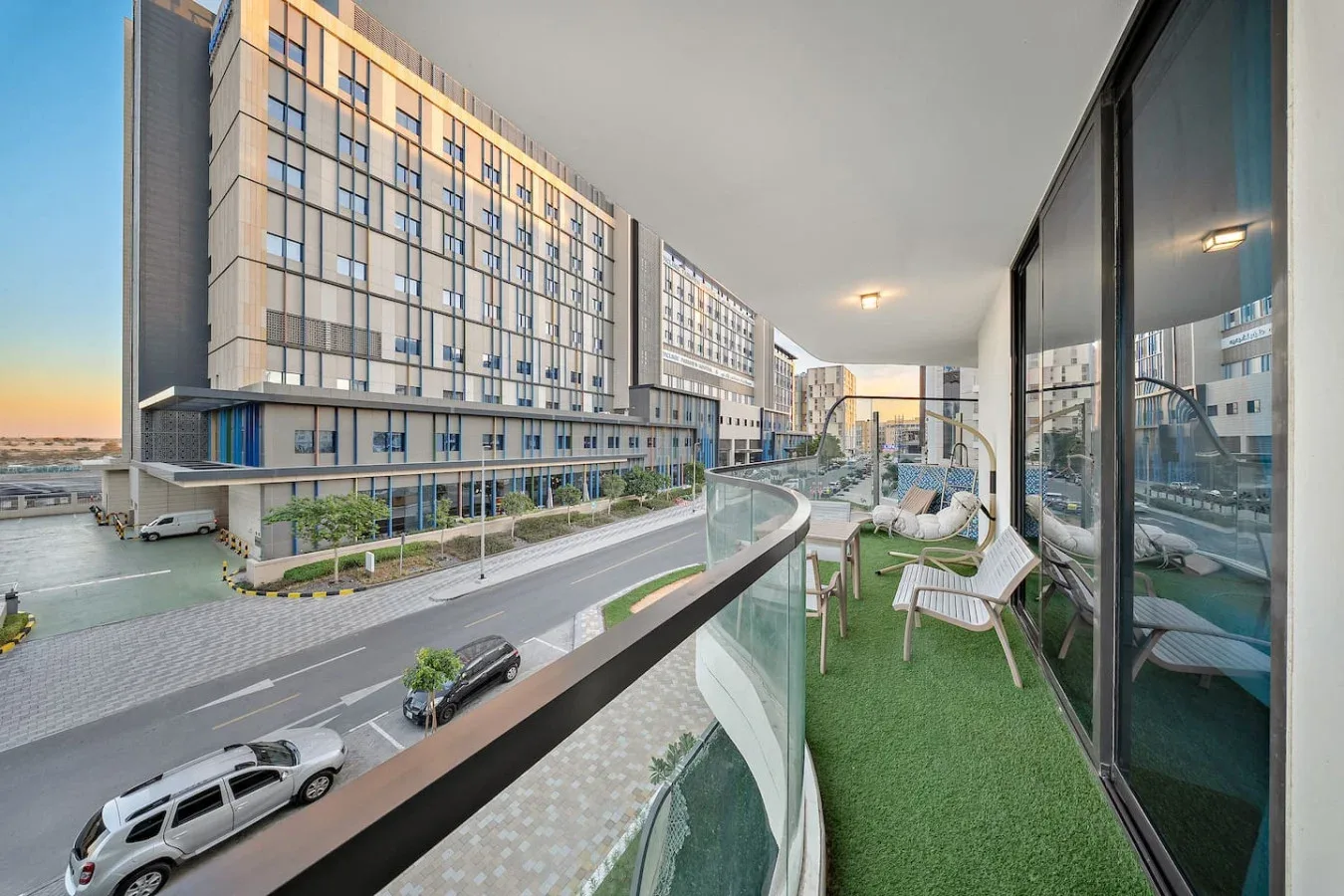 A balcony with outdoor seating overlooks a road and modern buildings.