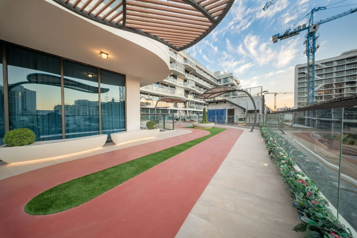 A landscaped walkway beside a modern building, with curved paving and glass windows.
